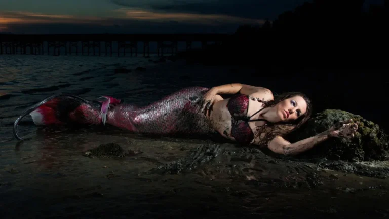 Shannon Scott dressed as a mermaid, posing gracefully near the ocean with flowing hair and a shimmering tail to show the freeing nature of Mermaid Retreats.