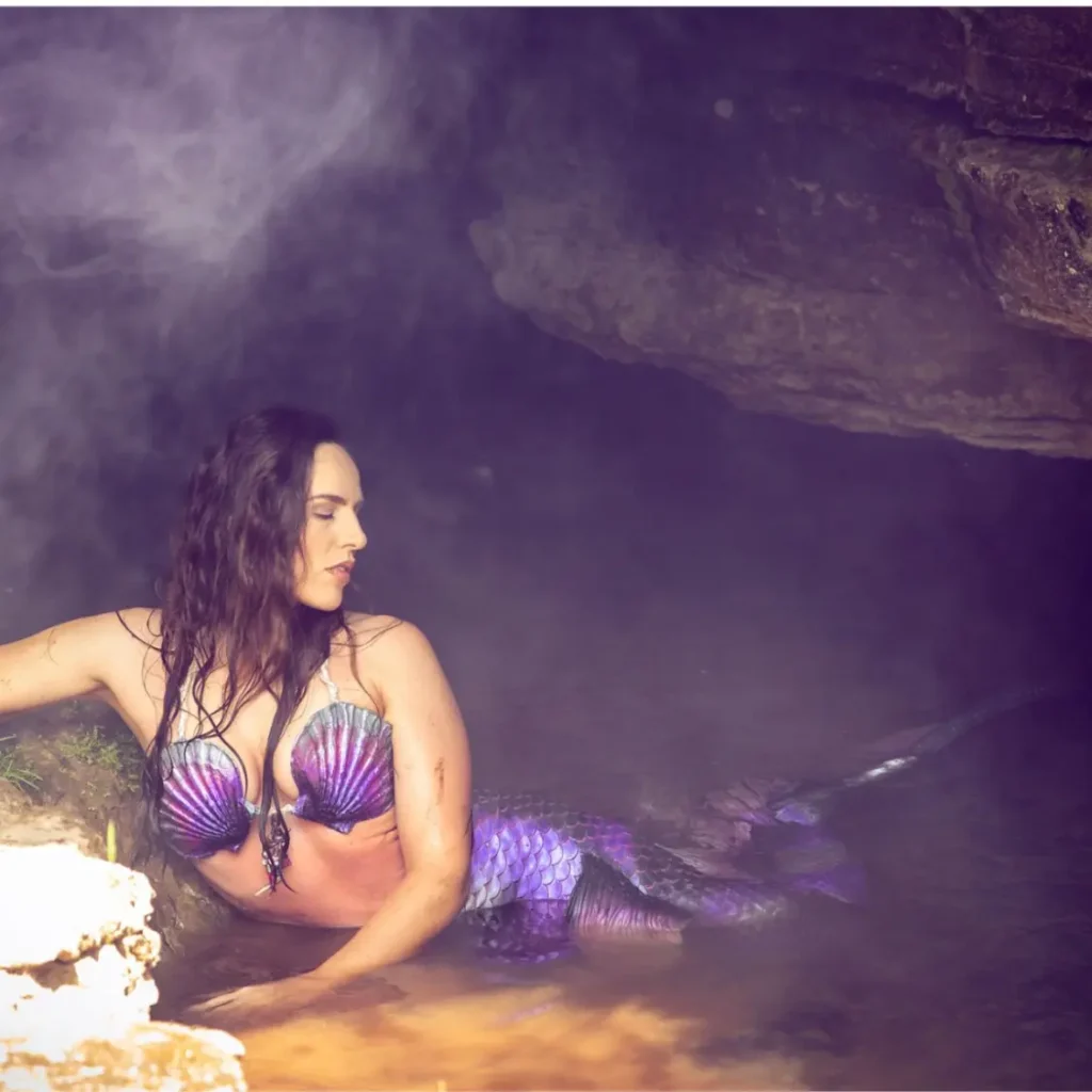 Shannon Scott as a mystical mermaid posing inside a dimly lit cave, creating an enchanting and spooky underwater atmosphere, showing the power of a spooky mermaid experience.