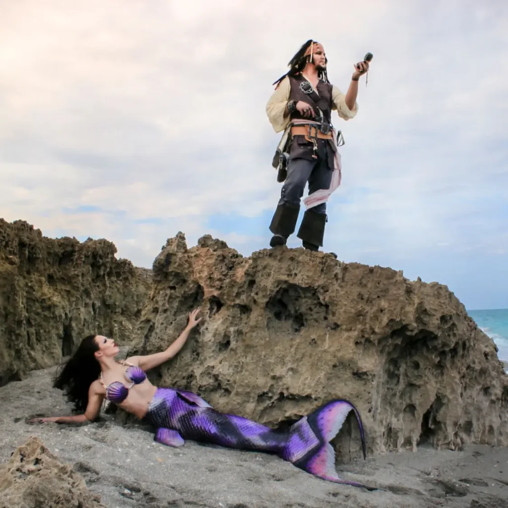 Captain Jack Sparrow poses alongside professional mermaid Shannon Scott, both in full costume, on the beach during a Halloween retreat for artists and creatives. This is where transformation through creativity begins.