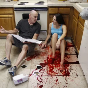 Actress Shannon Scott lying on the floor on a film set talking to director Mark Dossett, sitting in fake blood, during an intense and emotional performance moment.