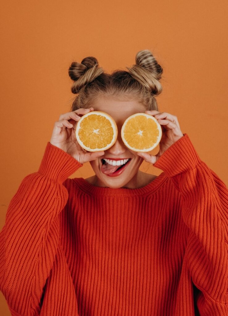 Playful young woman with oranges over her eyes representing The essence behind every creative retreat for actors at The Bright Stars Greenroom. 
