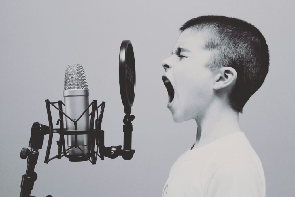 Boy passionately projecting his voice into a microphone, symbolizing vocal training for actors.