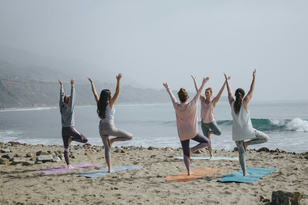 Actors practicing yoga on a beach as part of self-care for actors
