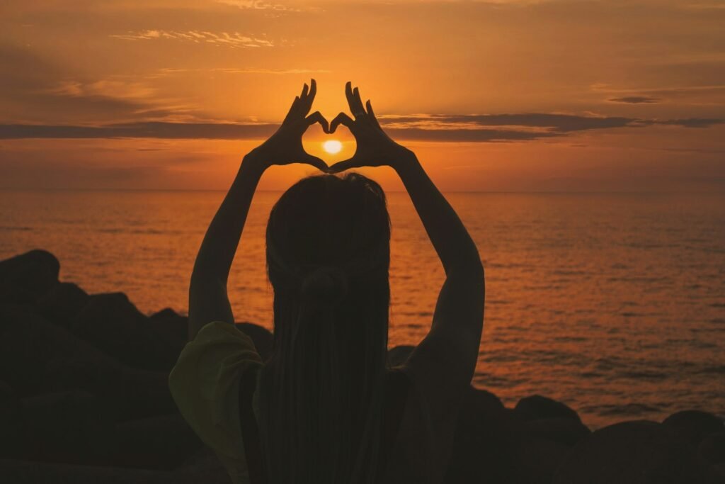 Silhouette of a girl making a heart shape with her hands against a sunset background, symbolizing acting career tips and inspiration.