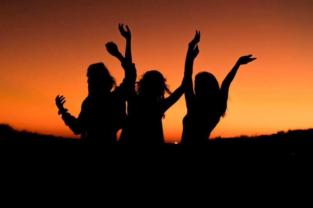 Silhouette of three people joyfully celebrating at sunset, symbolizing connection, growth, and transformation during one of our retreats for actors.