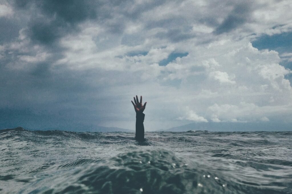 Hand rising from ocean water, symbolizing emotional release and full creative burnout recovery