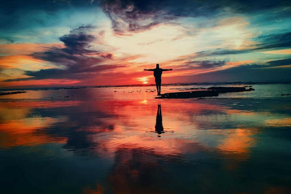 An artist standing on the beach during a spiritual retreat for creatives, reflecting in solitude and connection with nature