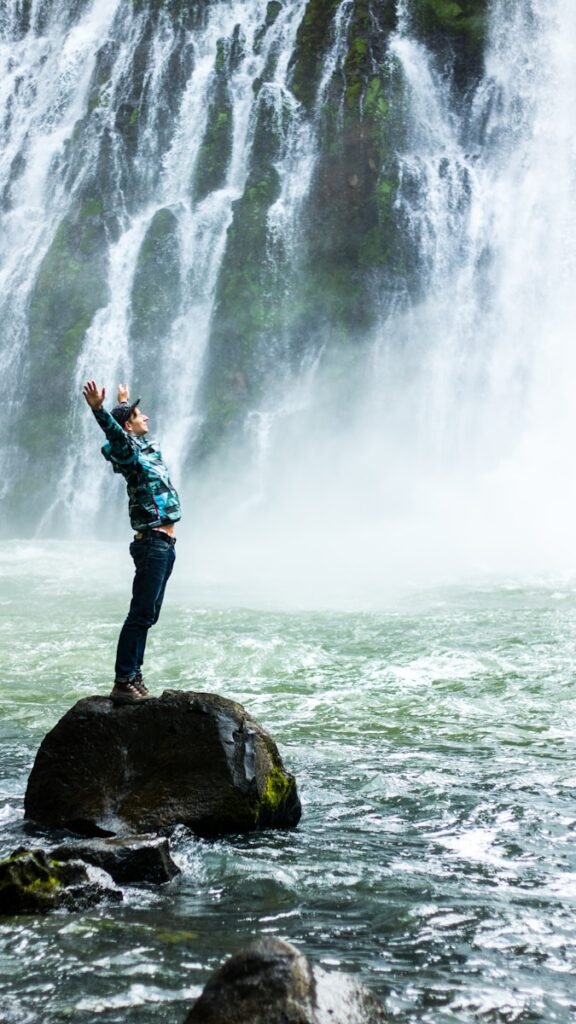 At creative wellness retreats, you'll be celebrating the rebith of your imagination like this man standing on black rock surrounded body of water