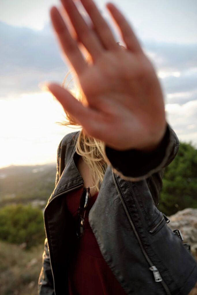 Woman holding her hand in front of the camera lens to symbolize consent and personal boundaries in modeling.