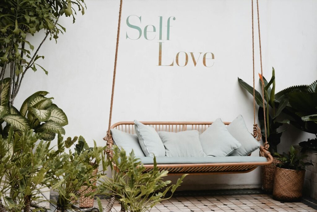 Cozy swing surrounded by plants and a “self love” sign, symbolizing acting industry self-care and nurturing creativity.