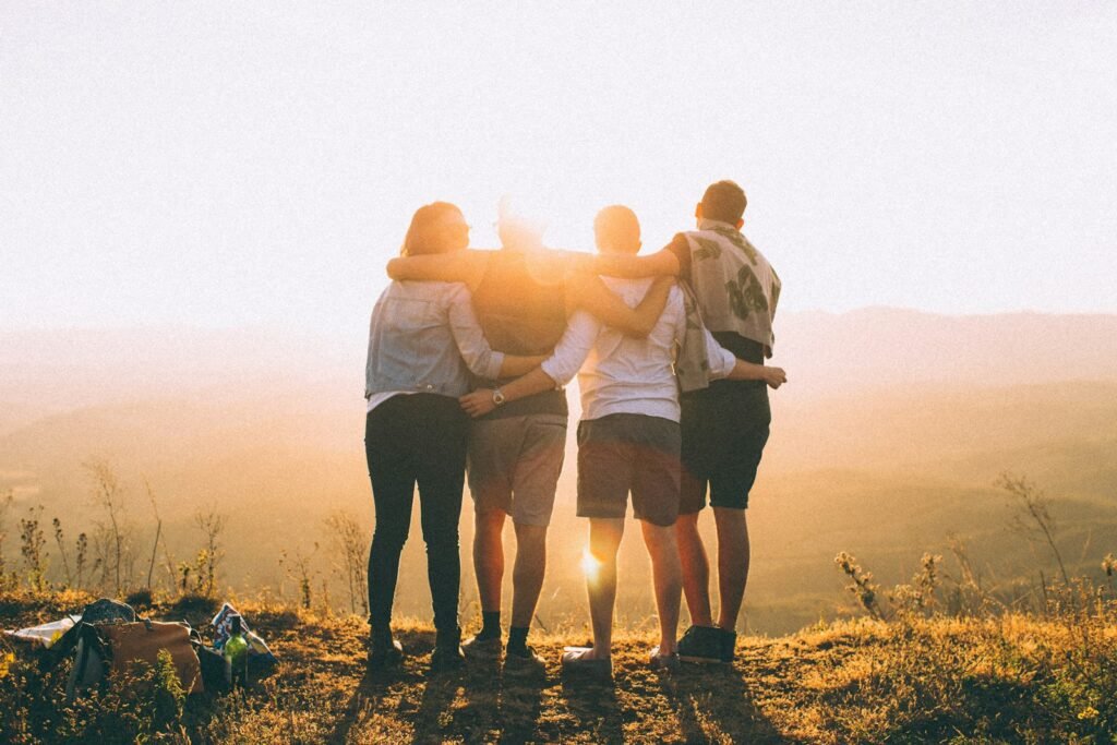Group of friends standing side by side, watching the sunset in silence—capturing a quiet moment that reflects the weight of creative burnout.