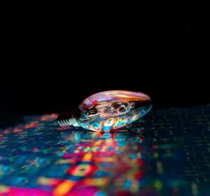 A lightbulb lying unlit on a swirl of vibrant colors, symbolizing ideas and energy waiting to awaken through creative retreat transformation.