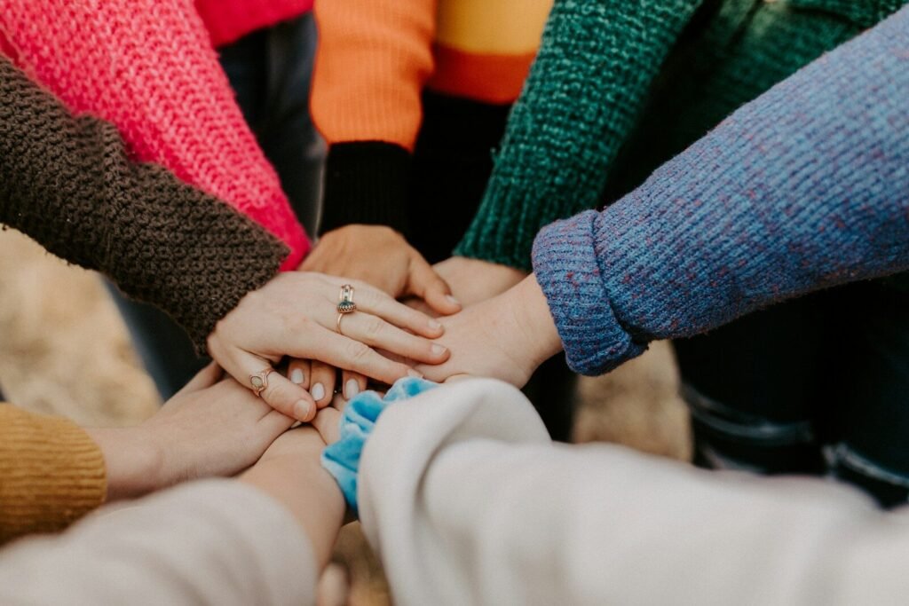 Women stacking hands together in circle, symbolizing unity at a women's fantasy retreat